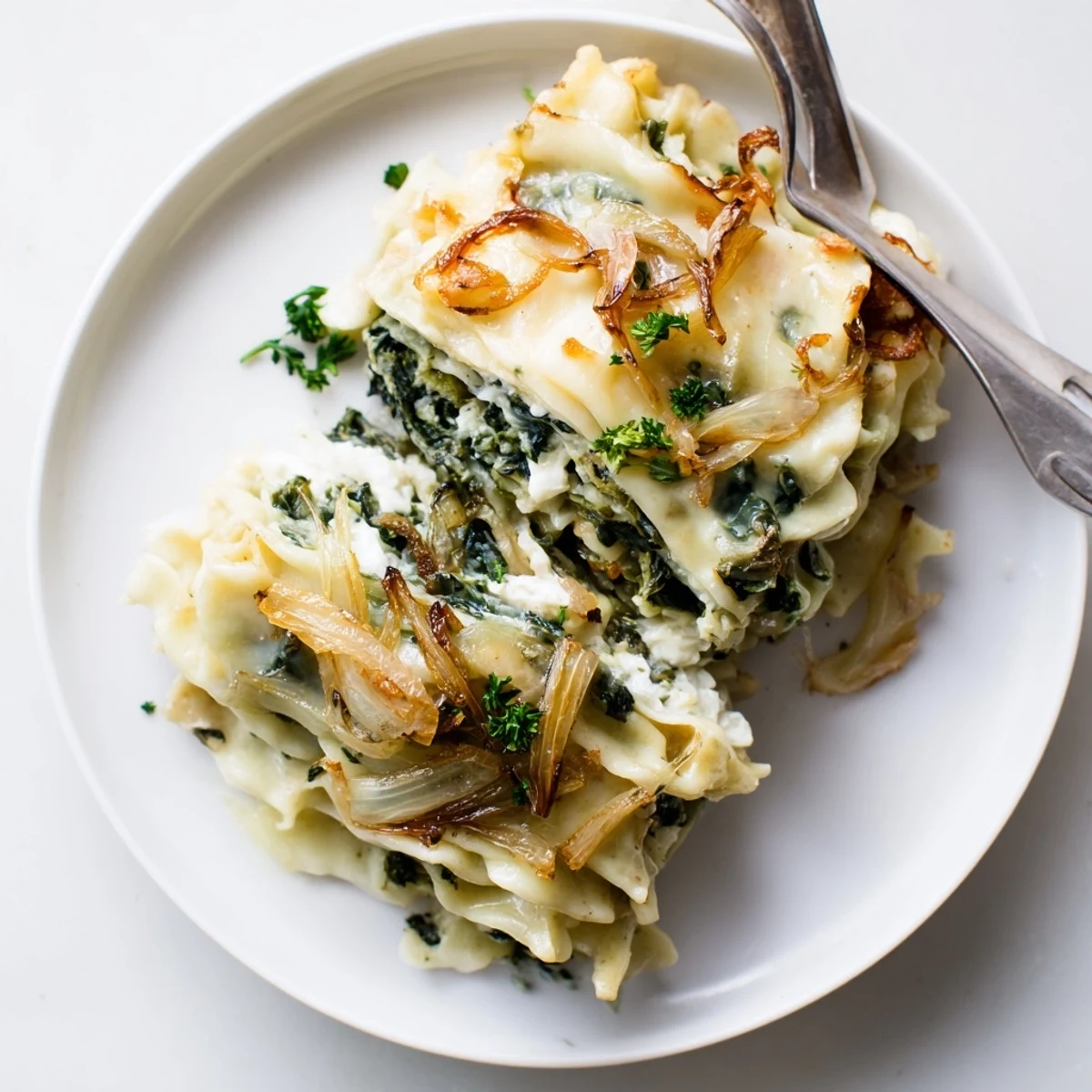 Pillowige Spätzle mit geschmolzenem Käse, angereichert durch lebendigen Spinat und Zwiebeln.  