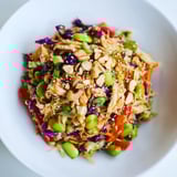 Gesunder Edamame Crunch Hähnchensalat mit glasierten Nüssen und leuchtenden Karottenstreifen auf dem Teller.  