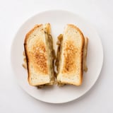 Golden-brown grilled sandwich slices with melted Gruyère cheese and sweet caramelized onions peeking out of crispy country bread.