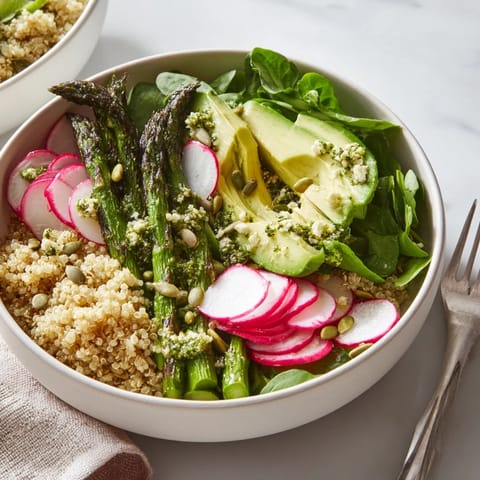 Bunte Quinoa-Schüssel mit Avocado, Spargel und Radieschen, ideal für eine leichte Mahlzeit.  